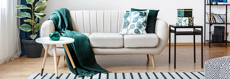 A living room with a white sofa, throw pillows, and a table with decorative boxes