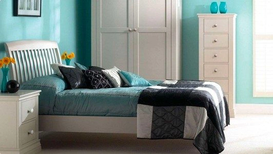 A blue coloured bedroom with a bed, side table, cupboard.