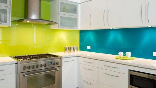 A modular white kitchen with lime green and blue wall.