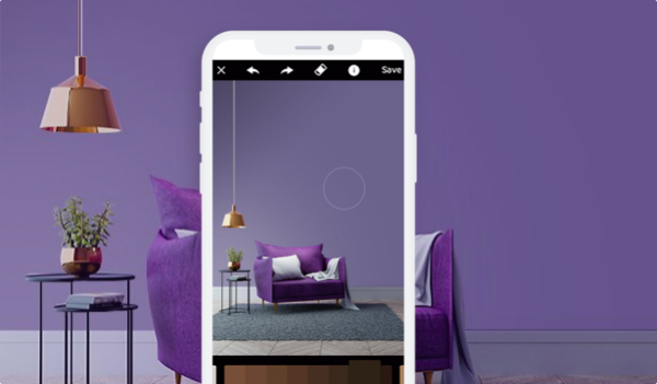 A mobile phone capturing an accent chair decorated with a cushion against purple walls.