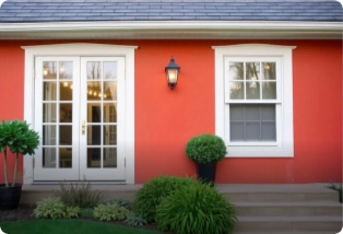 An exterior wall with white framed windows and red paint. Find painting contractors trusted by Asian Paints.