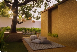 An outdoor seating area with cushions, warm lighting, and greenery, featuring a tree and textured walls. Find trusted painting contractors by Asian Paints.