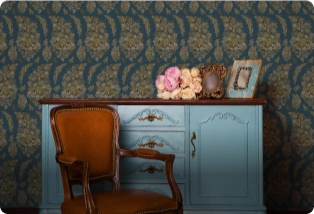 A living room featuring patterned wallpaper, a vintage cabinet, and an upholstered chair. Wallpaper contractors for your home.