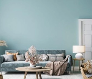 Fully Furnished Living Room with Blue Sofa, Center Table, Side Table, and Pastel Blue Walls. Interior Wall Painting Service by  Asian Paints.